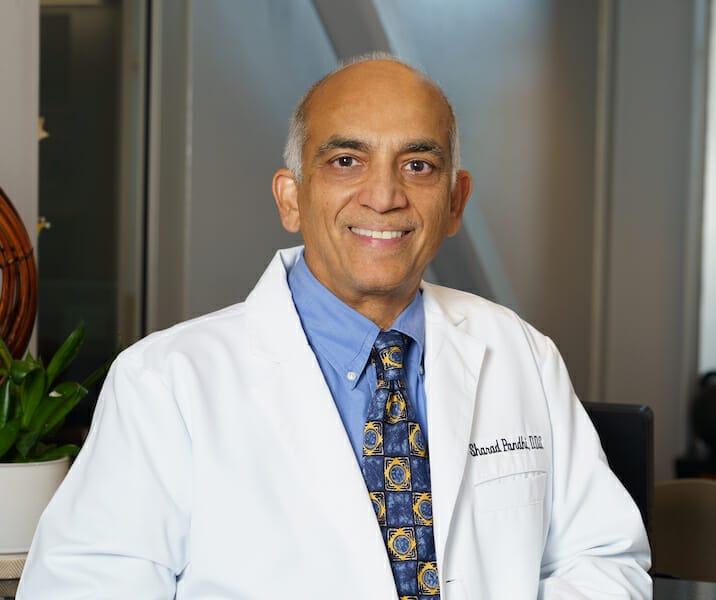 Dr. Sharad Pandhi in white lab coat and blue shirt with tie