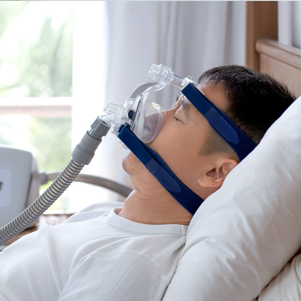 Man in bed with sleep apnea face mask