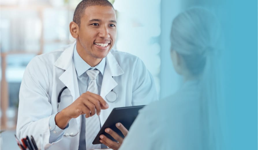 Smiling doctor holding a tablet while talking to a patient during a consultation