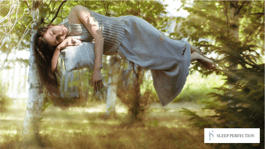 A woman appearing to levitate while sleeping outdoors between trees, dreamlike imagery