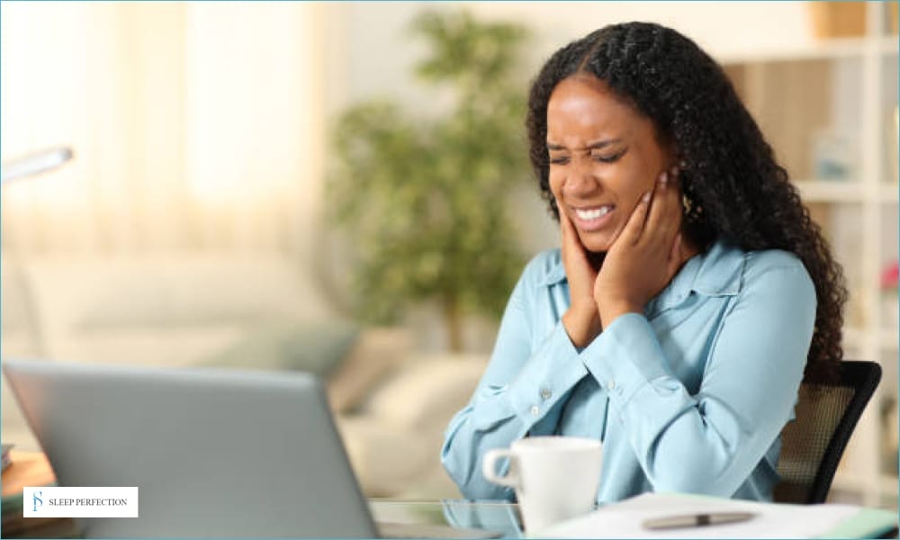 A woman sitting with a hand on her jaw, visibly experiencing pain or discomfort, symbolizing jaw-related issues such as TMJ pain